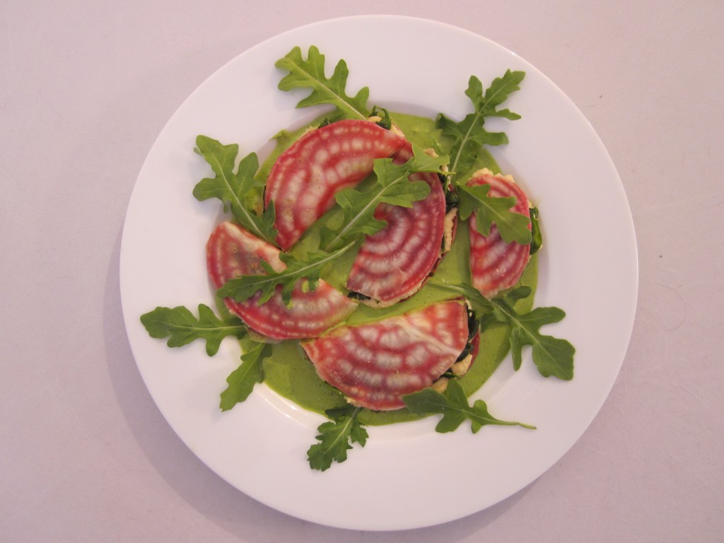 Beet Ravioli with Cashew Cheese, Wilted Spinach and Rocket Sauce plated